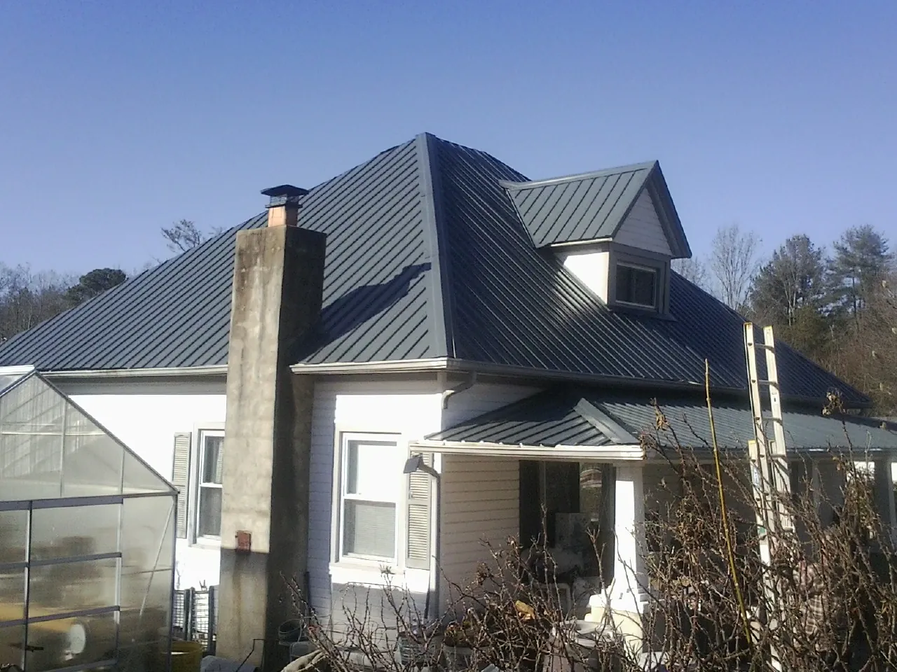 Dark blue standing seam metal roof on a white farmhouse with dormer — Slate & Tile Roof Repair by Roofing Brothers in Santa Clarita