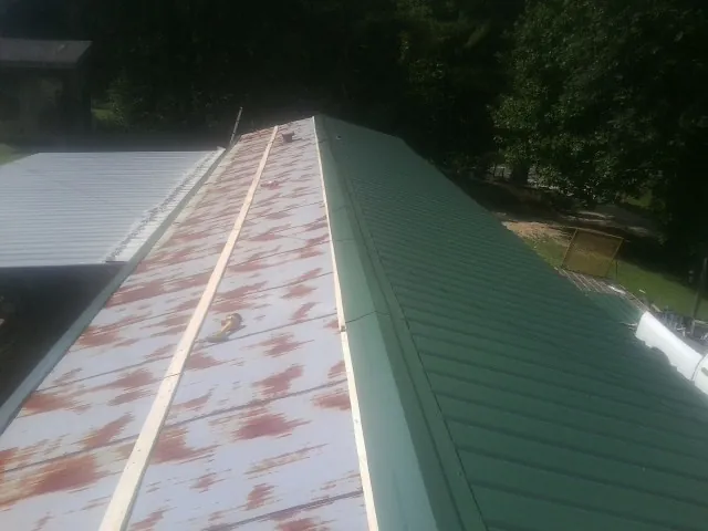 Old rusted panels beside newly installed green metal roofing — Wind Damage Roof Repair by Roofing Brothers in Santa Clarita