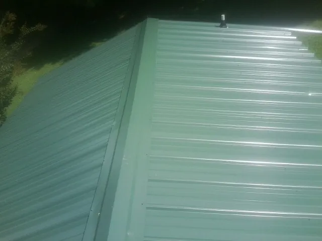 New green metal panels meeting at the ridge of a roof — Flat Roof Repair work by our crew in Santa Clarita