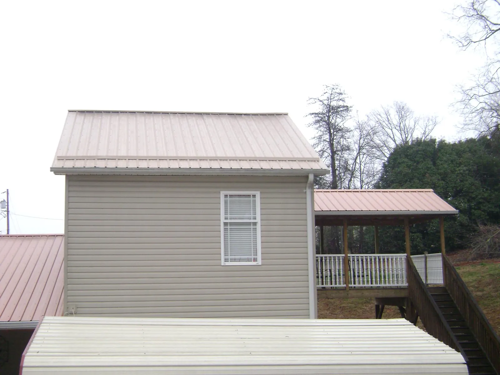 Tan metal roofs on a two story addition and attached porch, from a Roof Replacement job in Santa Clarita